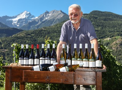 Il proprietario di Maison Anselmet con i suoi vini e, sullo sfondo, la Grivola