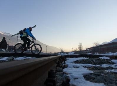 In bici portando gli sci verso la partenza della telecabina Aosta-Pila